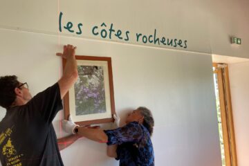 Deux employés de l'écomusée installent les cadres photos lors du montage de la nouvelle exposition temporaire